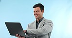 Laptop, smile and businessman typing in studio for legal case report on the internet with technology. Happy, corporate and professional male lawyer from Canada working on computer by blue background.