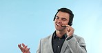 Customer support, smile and man consultant in a studio working on an online consultation for sales. Call center, contact us and young male telemarketing agent talking with headset by blue background.