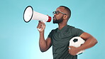 Football coach, man and megaphone in blue studio background, shouting and cheering with passion, pointing and energy. Soccer ball, person and loud voice for motivation, goals and team winning streak