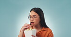 Face, popcorn and a woman watching tv or a movie in studio on a gray background for streaming entertainment. Horror video, junk food and a young person eating a cinema snack while looking scared