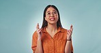 Hope, face and woman with fingers crossed in studio for feedback, results or review on blue background. Anxiety, stress or lady model with good luck emoji for wish, competition or winner announcement