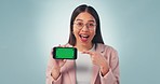 Green screen, phone and woman face with hand pointing agreement in studio with platform deal on blue background. Smartphone, space and portrait of female model show sign up, app or news promo support