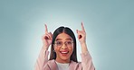 Happy, face and woman pointing up in studio with platform, agreement or promotion on blue background. Smile, portrait and excited female model with emoji hands for branding, support or service info