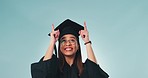 Face, graduation and woman with achievement, pointing up and opportunity on a blue studio background. Portrait, person and model with hand gesture, education and celebration with future and success