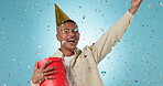 Birthday present, excited with black man and confetti shower in studio, celebration and giveaway on blue background. Happiness, cheers and winning with gift box, party with reward or bonus prize 