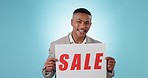 Discount, banner and face of happy man in studio with yes sale, deal or announcement on blue background. Billboard, promo code and portrait of guy model with retail, poster or news, offer or cashback