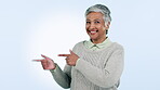 Smile, branding and pointing with a senior woman in studio on a blue background for marketing. Portrait, advertising and review with a happy elderly person looking excited by a sale, deal or offer