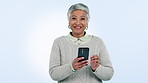 Phone, wow and surprise with a senior woman in studio on a blue background as the winner of a prize. Portrait, smile and communication with an elderly person in celebration of a bonus or good news