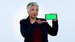 Face of businesswoman, show or green screen on a phone for social media advertising or online branding. Blue background, talk or mature lady pointing to mobile app chroma key mockup space in studio