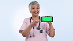 Green screen, senior or face of doctor with phone to research for medical mockup space in studio. Telehealth, woman or happy mature healthcare professional for advice on mobile app on blue background