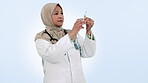 Muslim woman, medical doctor and needle in studio for healthcare, medicine or wellness. Hijab, mature and professional person with a syringe, injection and white background with liquid vaccine