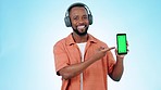 Black man, headphones and phone green screen for music, advertising or marketing against a studio background. Portrait of African male person smile with mobile smartphone app, display or mockup space