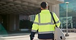 Man, back and architect walking in city for construction, maintenance or building at outdoor site. Rear view of male person, engineer or contractor carrying bag for project, architecture or plan