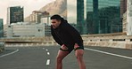 Breathing, road and fitness of tired man with rest from training, exercise and workout on city street. Marathon, runner and wellness of a athlete relax from running outdoor with sport and fatigue