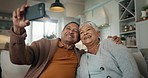 Senior couple, home and selfie while laughing on sofa and enjoying retirement together. Phone, smile and happy pensioners in family house, embracing each other and playful energy as elderly people