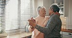 Senior couple, dancing and love in retirement, home and kitchen with kiss, care and support together in living room. Happy, elderly people and dance with freedom, peace and happiness in marriage