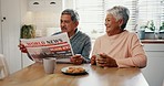 Senior couple, reading and newspaper in home with happy, announcement or press story, article or paper newsletter. People, together and morning in kitchen with news, discussion or journalist report