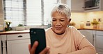 Video call, phone and senior woman in the kitchen waving for hello with communication at home. Technology, happy and elderly female person from Mexico on virtual conversation with cellphone at house.