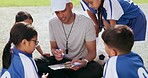 Coaching, clipboard and children on field for soccer prepare for game, match and practice outdoors. Sports, teamwork and young kids huddle for training formation, exercise and planning for tournament