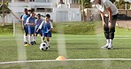 Soccer, kids kicking and training for game and sport drill for workout and exercise on a school field. Students, coaching and children with teamwork, player and team together with youth and group