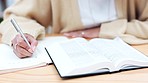 Hands, writing and book for bible study, woman or spiritual  growth with knowledge, faith and religion. Person, reading and notes with Christian scripture for peace, praise or worship at desk in home