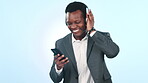 Black man, business and headphones with dancing, smartphone for music, listen to radio in studio on blue background. Corporate employee has fun with energy, rave or techno with audio streaming on app