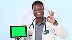 Doctor, tablet green screen and presentation with yes or okay hands for healthcare and clinic information on blue background. Face of black man on digital mockup or medical tracking marker in studio