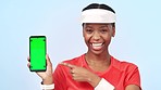 Woman, pointing and technology with green screen for health in studio for mockup with chromakey on blue background. Black, person or athlete with phone, smile or happy for offer in wellness on app