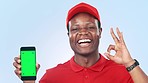 Happy black man, phone and pointing to green screen with OK emoji against a studio background. Portrait of African male person showing mobile smartphone app, display or mockup with tracking markers