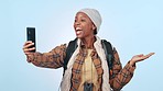 Hiking, video call and black woman with hand pointing to mockup in studio for travel or adventure on blue background. Backpacking, journey and African lady influencer live streaming blog or podcast