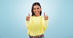 Face, thumbs up or happy woman laughing by mockup space isolated on blue background in studio. Winner, support or excited Indian girl smiling with like icon, agreement success or yes symbol for hope