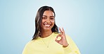 Happy, smile and face of woman in a studio with an ok, agreement and approval hand gesture. Happiness, excited and portrait of young Indian female model with perfect sign isolated by blue background.