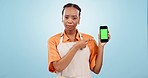 Black woman, waitress and phone pointing to green screen in advertising against a studio background. Portrait of African female or small business owner showing mobile smartphone app display or mockup