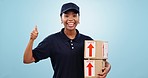 Happy black woman, box and thumbs up for delivery success or logistics against a blue studio background. Portrait of female person or courier lady smile with like emoji, yes sign or OK for package
