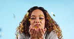 Woman, blowing glitter and happy in studio, success and celebration for achievement by blue background. Girl, confetti and excited face with smile, party or winning with decoration in portrait