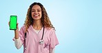 Portrait of woman doctor pointing at phone with green screen, mockup and tracking marker in studio. Smile, telehealth and happy nurse with smartphone chromakey, feedback or website on blue background