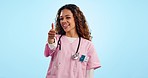 Face, doctor and woman with thumbs up, support and promotion on a blue studio background. Portrait, person and medical professional with hand gesture, feedback and review with like, icon and emoji