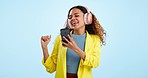 Dance, headphones and woman with phone in studio to celebrate freedom, karaoke party and audio on blue background. Happy model listening to mobile music, hearing radio and singing sound with energy 