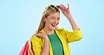 Fashion, sale and face of woman with shopping bag in studio with store, discount or promo on blue background. Retail deal and portrait of female customer excited for sunglasses, gift or accessories