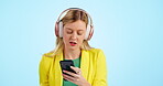 Woman, headphones and listening to music, dance with energy and mental health for creative marketing career in studio. Young business person with audio streaming service and mobile on blue background