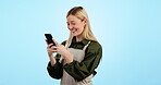 Business owner, waitress and woman with phone for social media, funny networking and cafe chat in studio. Young entrepreneur, barista or coffee shop typing on mobile and laughing on a blue background