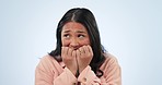 Nervous, anxiety and woman with fear, scared and depression on a blue studio background. Person, girl and model biting nails, emoji or sad with mental health, stress or thinking with terror or afraid