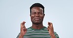 Hope, fingers crossed and black man in studio with anxiety for feedback, review or results on blue background. emoji, hands and African male model with please, gesture or miracle, waiting or suspense
