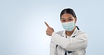 Studio woman, face mask and doctor pointing at hospital direction, clinic branding or pharmacy commercial. Pharmacist portrait, mockup space and surgeon advice, news or logo design on blue background