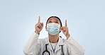 Studio woman, face mask and doctor pointing up at hospital direction, nursing health information or pharmacy info. Pharmacist support, mockup space and advertising surgeon portrait on blue background