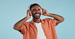 Black man, headphones and dancing to music with happiness and energy in studio on blue background. Techno, rave and fun with audio streaming, dancer is excited with smile and wireless technology