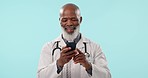 Senior, black man and doctor with phone for communication or Telehealth against a studio background. Happy mature African male person, medical or healthcare professional chatting on mobile smartphone