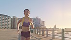 Beach, running and sports fitness of a woman runner by the sea, ocean and beach with speed. Exercise, marathon training and athlete run of a person doing a health workout on concrete outdoor