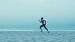 Woman, runner and on beach for training, fitness and workout for health, wellness or cardio. Female, girl or athlete running on sand, seaside or concentration with view, balance or practice for sport