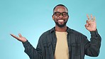 Smile, pointing and face of black man in a studio with mockup space for marketing or advertising. Happy, mock up and portrait of African male model with show hand gesture isolated by blue background.